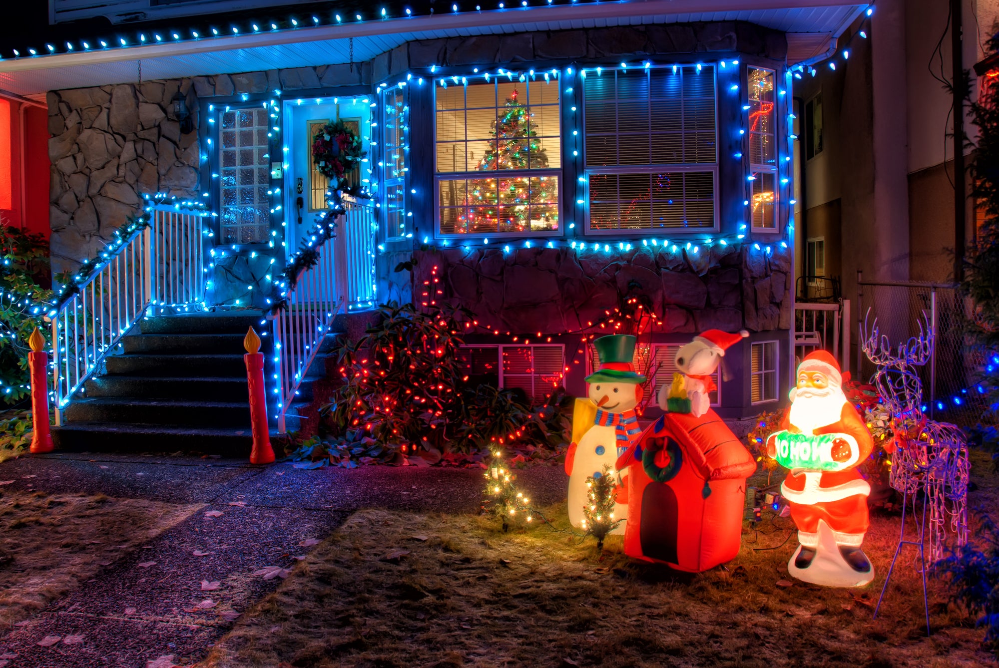 Decorated house with Christmas lights and inflatable Santa Claus figure in front.